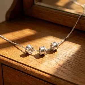 Dettaglio di una collana d'argento con perline distanziatrici su superficie in legno.