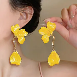 Close-up detail showing texture of yellow drip oil flower tassel earrings with golden stem