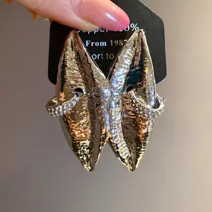 Close-up detail of vintage oversized metallic lip earrings with rhinestone ring embellishment