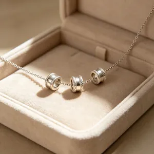 Dettaglio di tre perline d'argento a vita vuota su una catena delicata in una scatola regalo