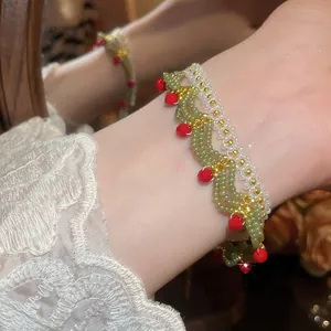 Detailed macro view of a handmade green and white glass beaded lace bracelet on a wrist