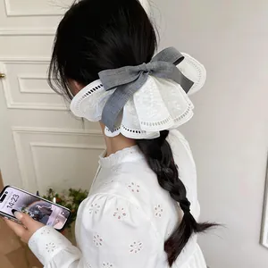 Detailed view of large white lace bow hair clip with grey ribbon on braided hair