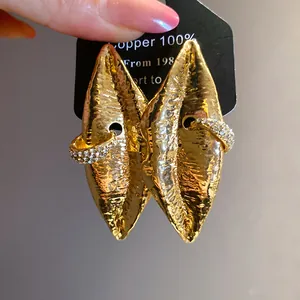 Macro detail of vintage gold lip-shaped earrings with sparkling rhinestone accents