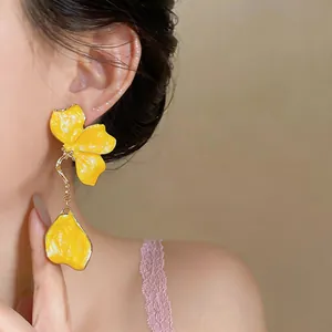 Detailed close-up of elegant bright yellow enamel flower tassel drop earrings on model