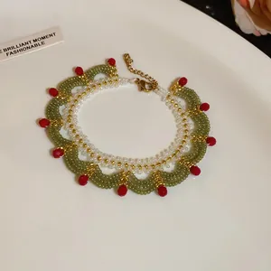 Close-up of handmade green and white beaded lace necklace with red accents