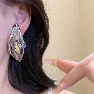 Close-up detail of textured silver-tone lip-shaped earring with sparkling rhinestone accents