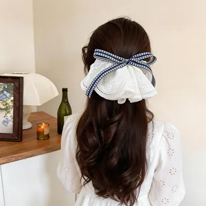 Elegant large white lace bow hair clip with navy gingham ribbon detail for women.