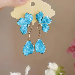 Macro detail of elegant blue marbled enamel flower drop earrings with golden hardware