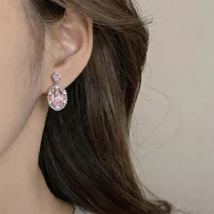 Nahaufnahme eines eleganten rosa ovalen Zirkon-Ohrrings, getragen von einem Modell
