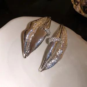 Detailed macro view of silver-tone textured lip-shaped earrings with rhinestone accents.