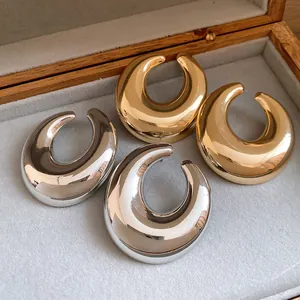 Dettaglio degli orecchini a mezzaluna in metallo lucido con finiture oro e argento