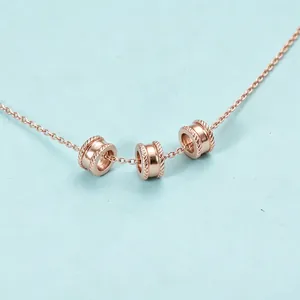 Primo piano di collana in oro rosa con tre perle distanziatrici cilindriche cave