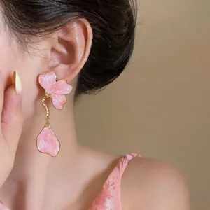 Elegant pink enamel flower drop earrings with golden trim shown on a model for detail view.