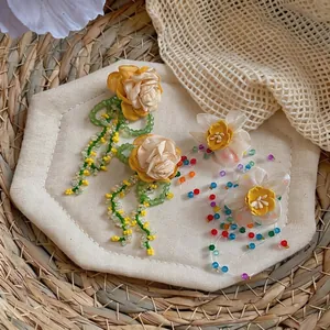 Elegant Korean style fabric flower earrings with colorful glass bead tassels on woven mat.