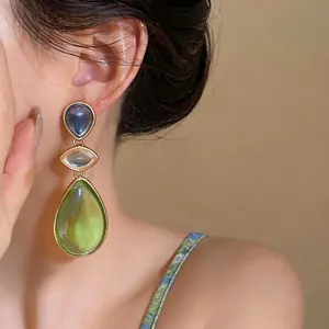 Elegant three-tiered resin teardrop earrings featuring a gold finish worn by a model