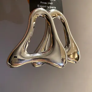 Primo piano di orecchini a perno a triangolo cavo color argento con finitura lucida
