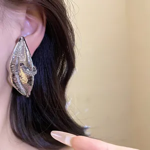 Detailed close-up of oversized silver lip-shaped earrings with rhinestone detail on ear.
