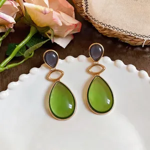 Elegant resin teardrop drop earrings with green and grey stones on a white plate