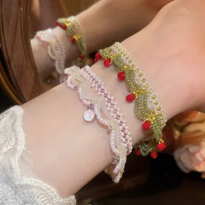 Close-up of handmade beaded bracelets with intricate lace patterns and glass pendants