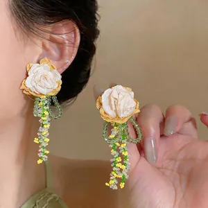 Korean style fabric rose stud earrings with green glass bead tassels shown on an Asian model