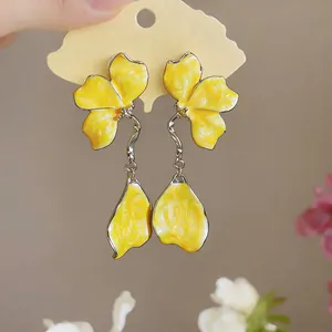 Detailed macro shot of elegant yellow enamel flower tassel earrings on display card