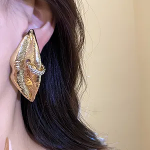 Detailed view of vintage gold lip-shaped earrings with a sparkling rhinestone-encrusted ring.