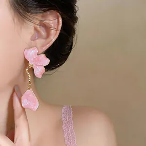 Macro detail shot showing a delicate pink flower petal drop earring on a model's ear
