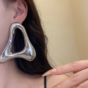 Dettaglio ravvicinato di un orecchino a triangolo d'argento minimalista oversize su una modella