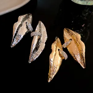 Detail view of avant-garde lip-shaped earrings with rhinestones in gold and silver.