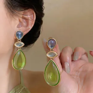 Detailed macro view of resin teardrop earrings with green and purple stones
