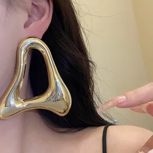 Dettaglio ravvicinato che mostra la finitura oro lucido degli orecchini a triangolo vuoti