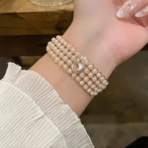 Dettaglio di un elegante bracciale di perle multistrato con ciondolo numero 5 scintillante
