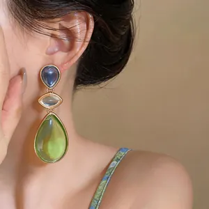 Detail shot of multi-colored resin drop earrings with a large green pear-shaped pendant