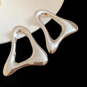 Dettaglio di orecchini a lobo a triangolo geometrico cavo con finitura argento lucido