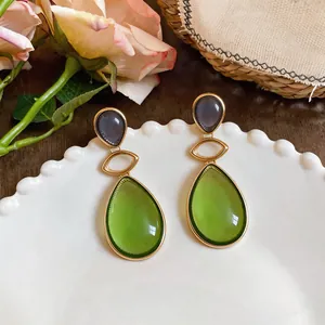 Detailed view of vintage resin teardrop earrings with green and gray tones on white plate.