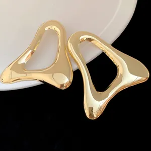 Dettaglio di orecchini a triangolo dorati cavi con finitura lucida e stile minimalista.