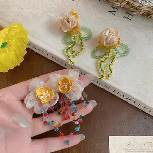 Detailed view of handmade fabric flower earrings with colorful glass bead tassels.