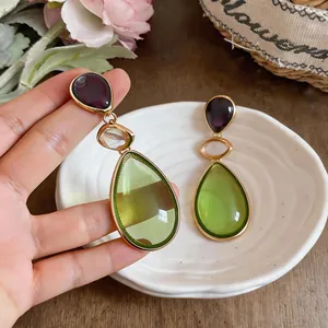 Macro view of translucent lime green resin drop earrings with gold-toned metal trim