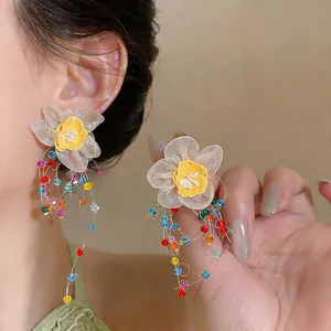 Detail shot of fabric flower earrings with colorful glass bead tassels on silver needles.