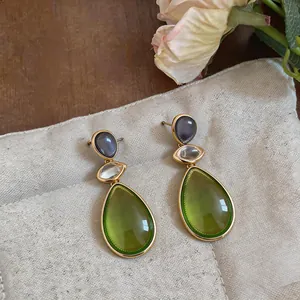 Close-up of elegant gold-toned drop earrings featuring vibrant green resin teardrop stones