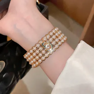 Dettaglio di bracciale di perle multistrato con logo CD in oro vintage sul polso