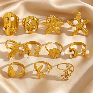 Vue détaillée de bagues en acier doré sur le thème de la mer avec perles et étoiles.