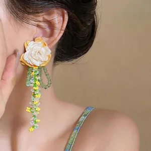 Detailed view of handmade fabric flower earrings with green glass beaded tassels on model