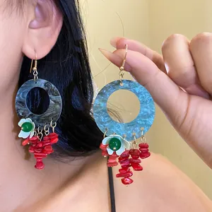 Close-up detail of ethnic colorful circular earrings with red tassel and flower