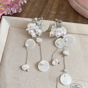 Close-up of French retro tassel earrings with faux pearls and shell discs