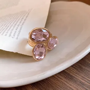 Close-up detail of a retro oval open ring featuring pink crystal rhinestones in a gold setting