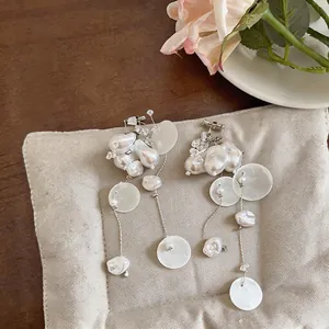 Detail shot of French retro faux pearl tassel ear clips on a textured linen cushion