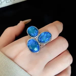 Detailed close-up of a vintage open ring with three oval blue crystals on finger