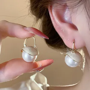 Macro view of French style pearl drop earrings with elegant cream enamel finish