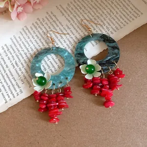 Macro view of Chinese style floral earrings with marbled resin hoops and red bead tassels